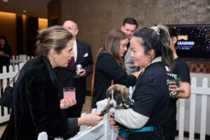 A woman holding a puppies paw at BC SPCA's Offleashed Vancouver Gala 2023