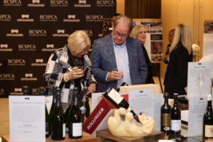 A couple with drinks looking at auction items at BC SPCA's Offleashed Vancouver Gala 2023