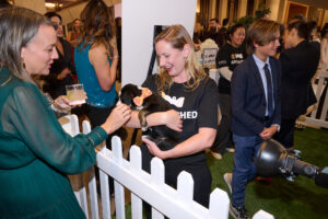 A woman greeting a puppy at BC SPCA's Offleashed Vancouver Gala 2023