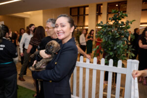 A smiling woman holding a puppy at BC SPCA's Offleashed Vancouver Gala 2023